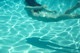 A woman floating in a swimming pool with her shadow on the water.