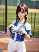 A woman in a baseball uniform standing on a baseball field.